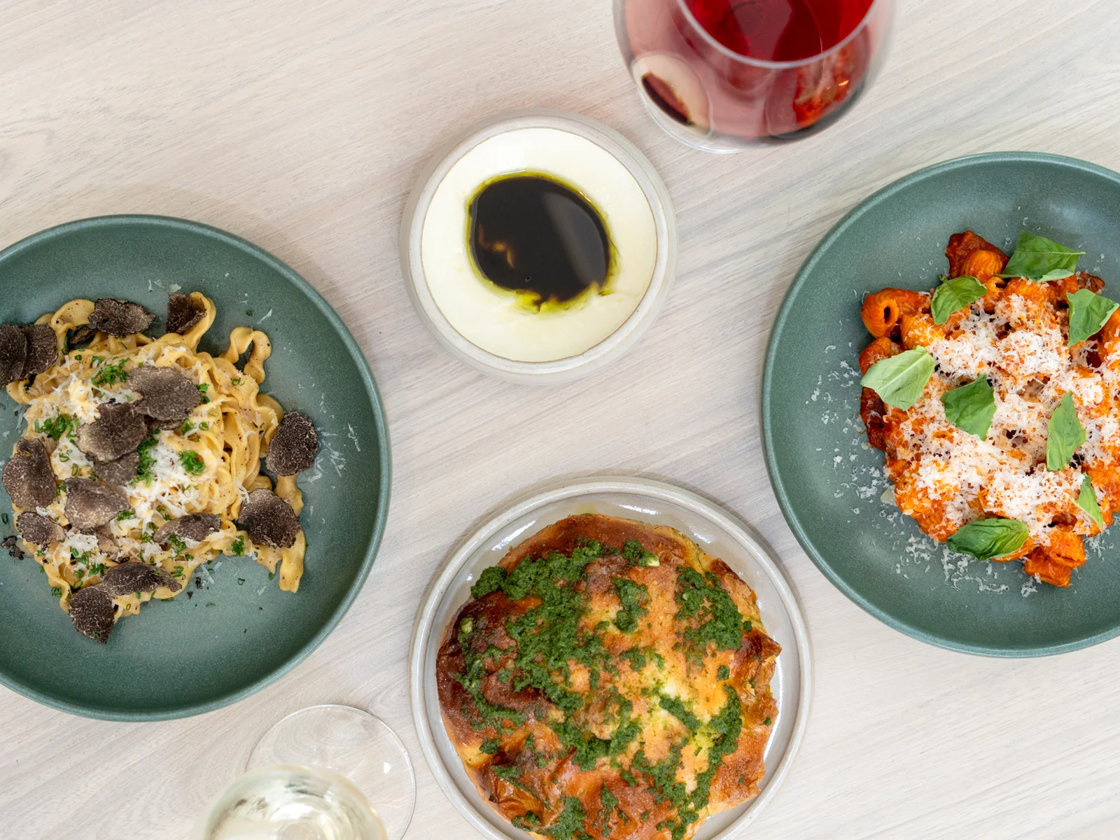 Overhead view of Ash pasta dishes including lumache alla vodka, truffle tagliatelle, focaccia, and wine
