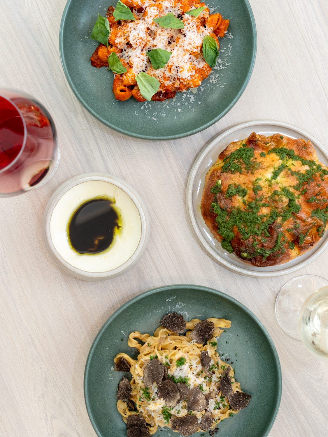 A spread of dishes at Ash including rigatoni vodka, focaccia, and truffle tagliatelle, paired with red and white wine