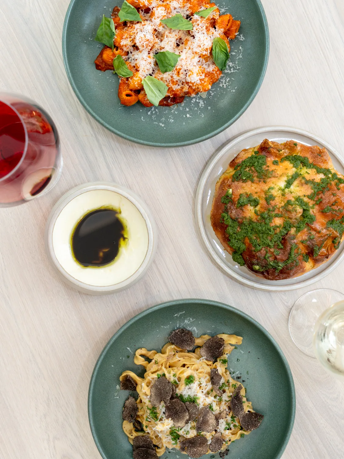 A spread of dishes at Ash including rigatoni vodka, focaccia, and pasta, paired with red and white wine
